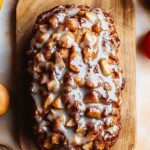 Amish Apple Fritter Bread: Sweet, Spiced, and Perfect for Fall 3 Freshly baked Amish apple fritter bread loaf with glaze on a wooden cutting board surrounded by autumn decor
