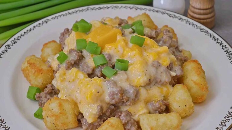 Slow Cooker Cowboy Casserole with beef, tater tots, cheese, and green onion topping on a plate.