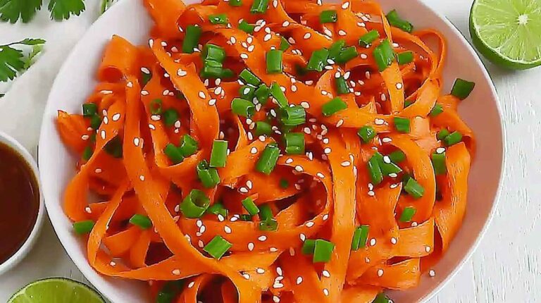 Vegan raw carrot salad with shaved ribbons, sesame seeds, and green onions