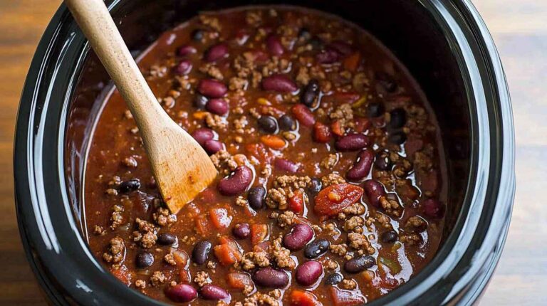 Slow Cooker Chili Recipe: The Ultimate Set-and-Forget Comfort Food 8 Hearty chili with beans and ground beef in a slow cooker, stirred with a wooden spoon.